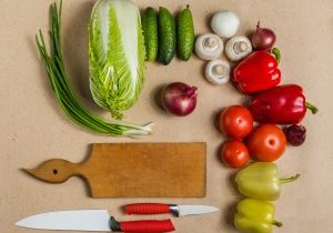 Composition of raw organic vegetabes with knife on kitchen table