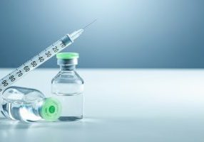 Vaccine in vial and syringe close-up on a white table gray background, medical concept, laboratory, subcutaneous injection vaccination, dose. Disease treatment immunization